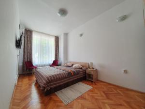 a bedroom with a bed with two red chairs and a window at STUDIO APARTMENTS in Alba Iulia