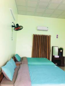 1 dormitorio con 1 cama grande con almohadas azules y rosas en Vy Ly Motel, en Phú Quí (2)