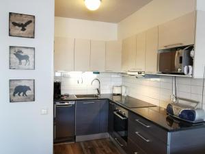 Una cocina con gabinetes blancos y electrodomésticos negros. en Näköalahuoneisto 413, en Syöte