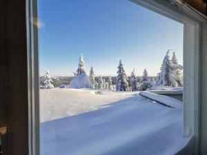 una ventana con vistas a un campo cubierto de nieve con árboles en Näköalahuoneisto 413, en Syöte