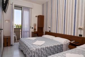 una camera d'albergo con due letti e una finestra di Hotel Atlantic a Rimini