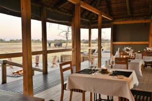 um restaurante com mesas e vista para um campo em Nogatsaa Pans Chobe Lodge em Kasane