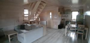 Przytulny domek في Darłówko: غرفة معيشة مع أريكة بيضاء ومطبخ