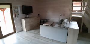 uma sala de estar com um sofá branco e uma televisão em Przytulny domek em Darłówko