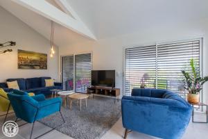 een woonkamer met blauwe banken en een tv bij Appartement Lac in Sévrier