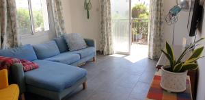a living room with a blue couch and a window at Athena and The Owl Beachside Apt in Paphos City