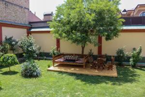 a garden with a bench and a table and a tree at Chinor Garden Hotel - Free Airport Pick-up and Drop-Off in Tashkent