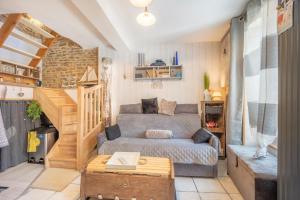 sala de estar con sofá y escalera en Le ptit passage en Saint-Aubin-sur-Mer