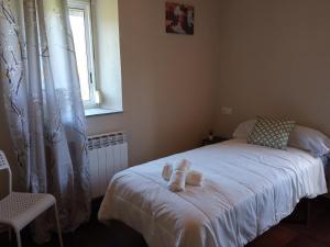 una camera da letto con un letto con lenzuola bianche e una finestra di CASA ISAURA DE PENA Camino Primitivo a Pacio