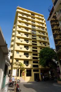 マレにあるムーカイ ホテルの高い黄色のアパートメントで、木が目の前に立つ