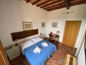 a bedroom with a bed with a blue bedspread at Rooms and Wine al Castello in Monteriggioni