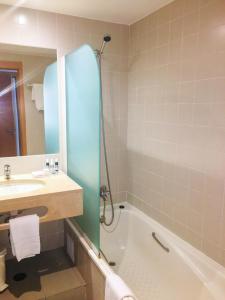 a bathroom with a sink and a tub and a mirror at Marina Club Lagos Resort in Lagos