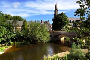 a bridge over a river with a building and a church at The Auction House in Morpeth