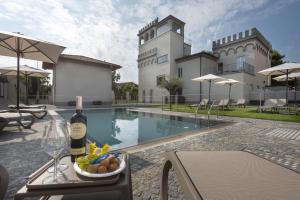 a table with a bottle of wine and a bowl of fruit next to a pool at VILLA BERNASCONI in Narzole