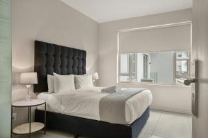 a bedroom with a large bed with a large window at Easy Stay - The Tyrwhitt Rosebank in Johannesburg
