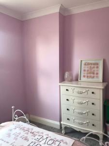 a bedroom with purple walls and a white dresser at A Wave From It All in Great Clacton