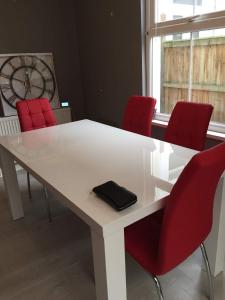 a white table with red chairs in a room at A Wave From It All in Great Clacton