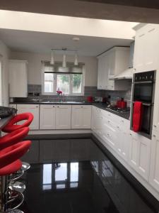 uma cozinha com armários brancos e cadeiras vermelhas em A Wave From It All em Great Clacton