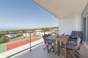 a dining table and chairs on a balcony with a tennis court at Muralha 2 - Holiday Apartments - By SCH in Nazaré