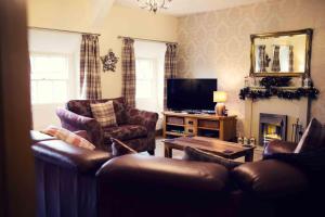 a living room with leather furniture and a television at Grade ll Georgian Apartment, Central Market Place in Barnard Castle