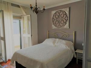 a bedroom with a white bed and a chandelier at Casa con PATIO en el centro de la Ciudad in Chiclana de la Frontera