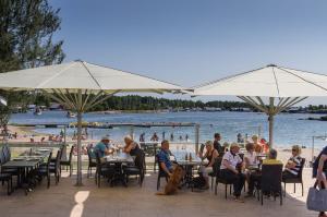 a group of people sitting at tables near a beach at Käringsund Resort in Eckerö