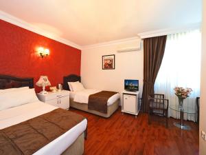 Habitación de hotel con 2 camas y pared roja en The Sunrise Hotel, en Estambul