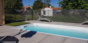 a swimming pool with a chair in a yard at Chez Marcel Gite PMR in La Marne