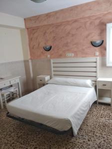 a bedroom with a white bed with a large headboard at Pensión Juan Pedro in Roquetas de Mar