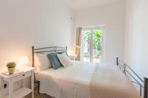 a white bedroom with a bed and a window at Villa Ferreri in Specchiolla 