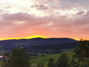 una puesta de sol sobre un campo verde con una montaña en Allgäuer Ausblick, en Missen-Wilhams