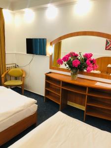 una camera d'albergo con scrivania, specchio e fiori di Hotel Taurus a Święta Lipka