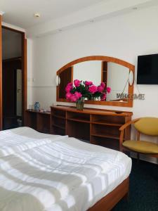 1 dormitorio con cama y escritorio con espejo en Hotel Taurus en Święta Lipka