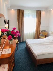 a hotel room with a bed and a desk with flowers at Hotel Taurus in Święta Lipka