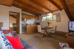 een woonkamer met een bank en een tafel en een keuken bij Chalet Romantica in Paihia