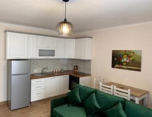 a living room with a green couch and a kitchen at Alb's Apartment 2 in Golem