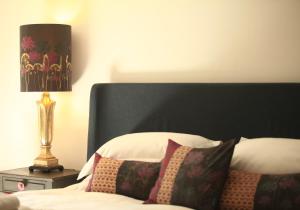 a bedroom with a bed with a black headboard and a lamp at The Lakehouse in Ugborough