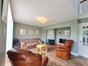 sala de estar con muebles de cuero y chimenea en 68 Clifden Glen, en Clifden