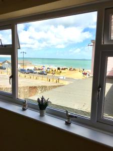 a window with a view of the beach at Pink Beach Holiday Apartments in Shanklin
