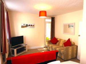 a living room with a couch and a television at Pink Beach Holiday Apartments in Shanklin