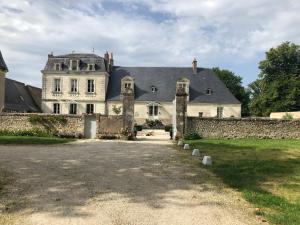 una grande casa bianca con un muro di pietra di Manoir de la Mazeraie, idéal pour le télétravail a Joué-lés-Tours