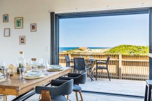 翁德雷的住宿－Villa Oceana vue exceptionnelle sur l'océan, haut standing, front de mer.，一间带桌椅和大窗户的用餐室