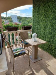 a table and chairs on a patio with a green wall at Apartman Lili in Rogoznica