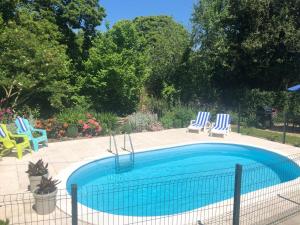 a swimming pool with two blue and white chairs at Walnut Tree Gite Brittany in Boderel