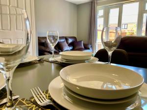 a table with plates and wine glasses on it at Queens Lodge - Beautiful Modern House with Free Parking - Marvello Properties in Norwich