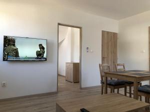 a living room with a table and a television on the wall at Pupos Apartman Szigliget in Szigliget