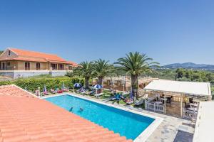 a resort with a swimming pool and palm trees at Kapetanios Apartments in Agios Stefanos