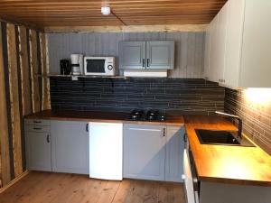 a small kitchen with white cabinets and a microwave at Storbo Adventure Camp in Storbo