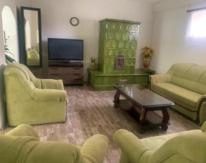 a living room with green furniture and a television at Viktor Apartmanház in Zamárdi