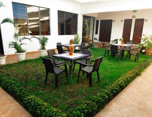 a patio with tables and chairs on the grass at Hostal Las Puertas in Santa Ana